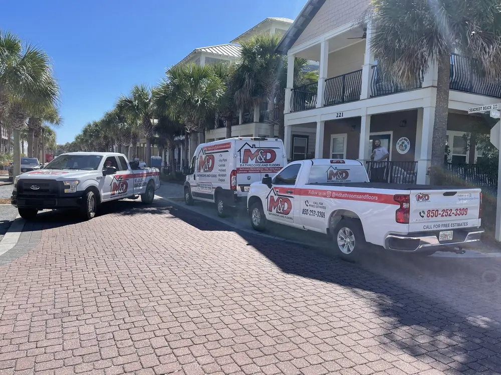 M&D trucks and a van parked on a palm-lined street