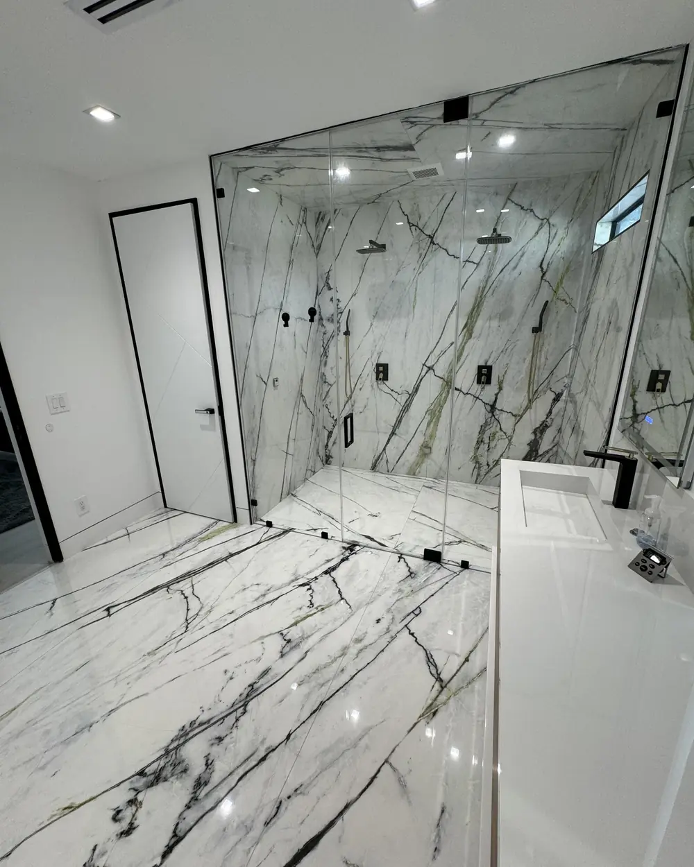 Walk-in shower and floor in dramatic black-veined marble-look tile